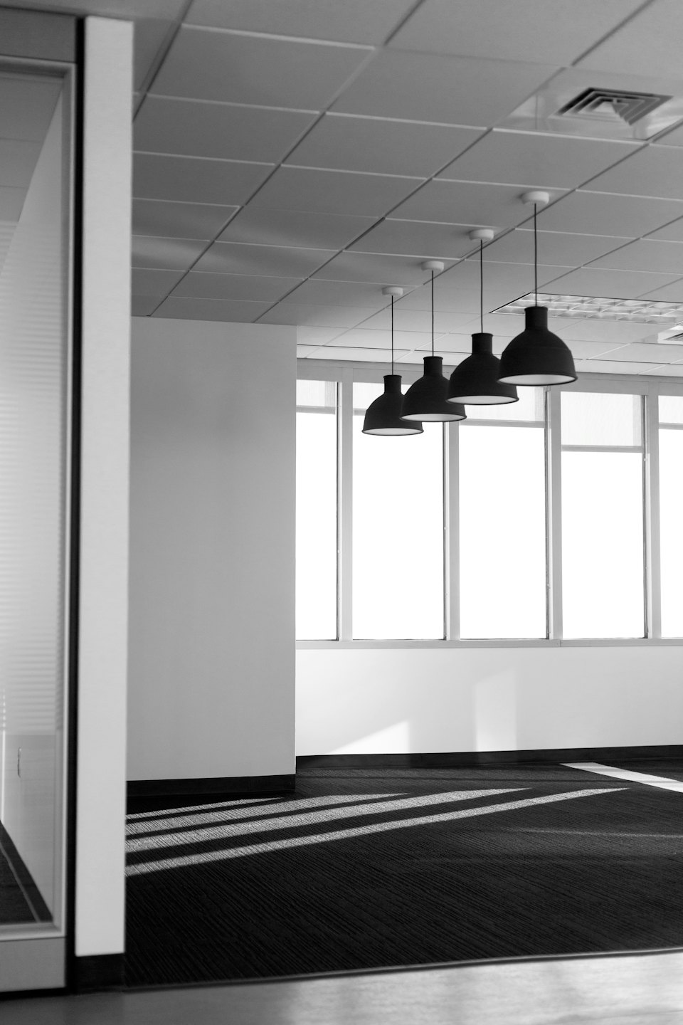 Brightly lit modern office space with large windows and pendant lights.
